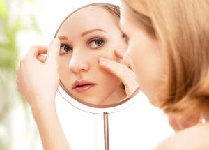 mulher olhando no espelho suas rugas nos olhos