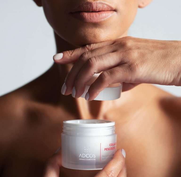Mulher jovem segurando em mãos o creme Collagen Pescoço e Colo, da ADCOS
