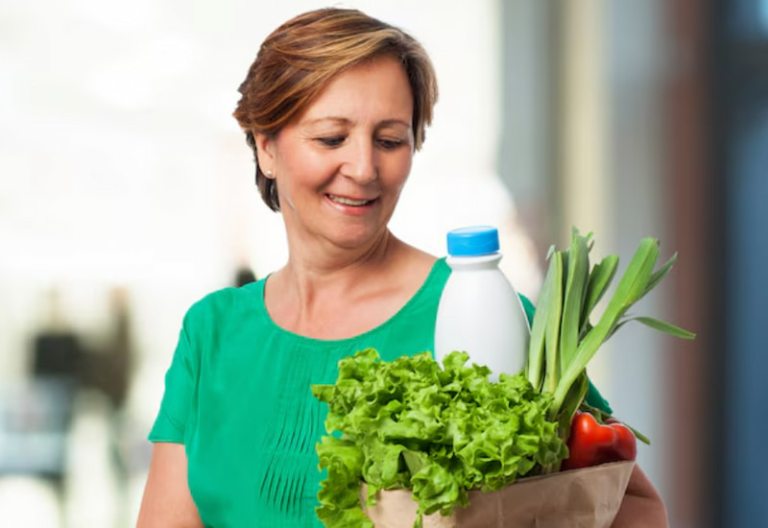 Mulher madura e serena segurando alimentos ricos em nutrientes, em ambiente claro